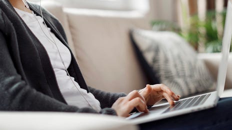 Young woman participating in an english group class online from home using a laptop and earphones.