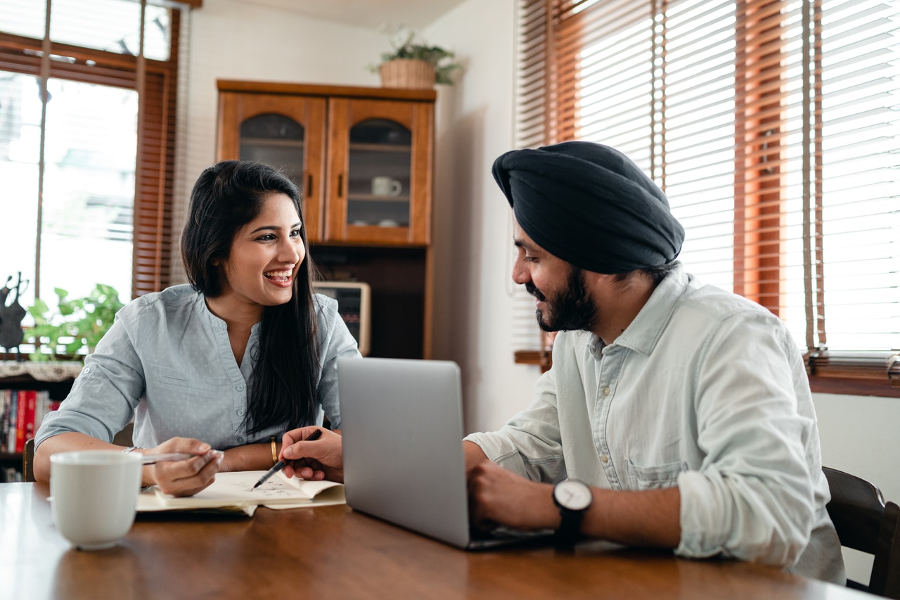 Happy couple discussing Indian languages and business at home over coffee