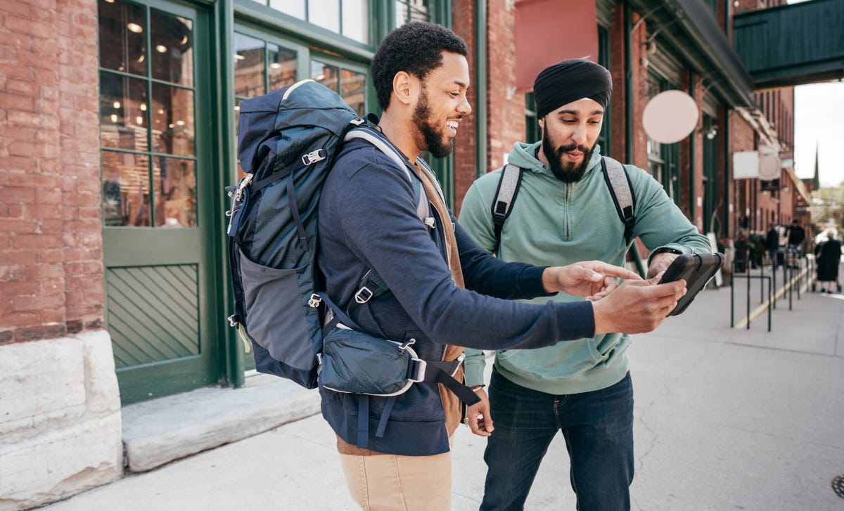 Two travelers using a smartphone on a city street, symbolizing the accessibility of intermediate German lessons for travelers.