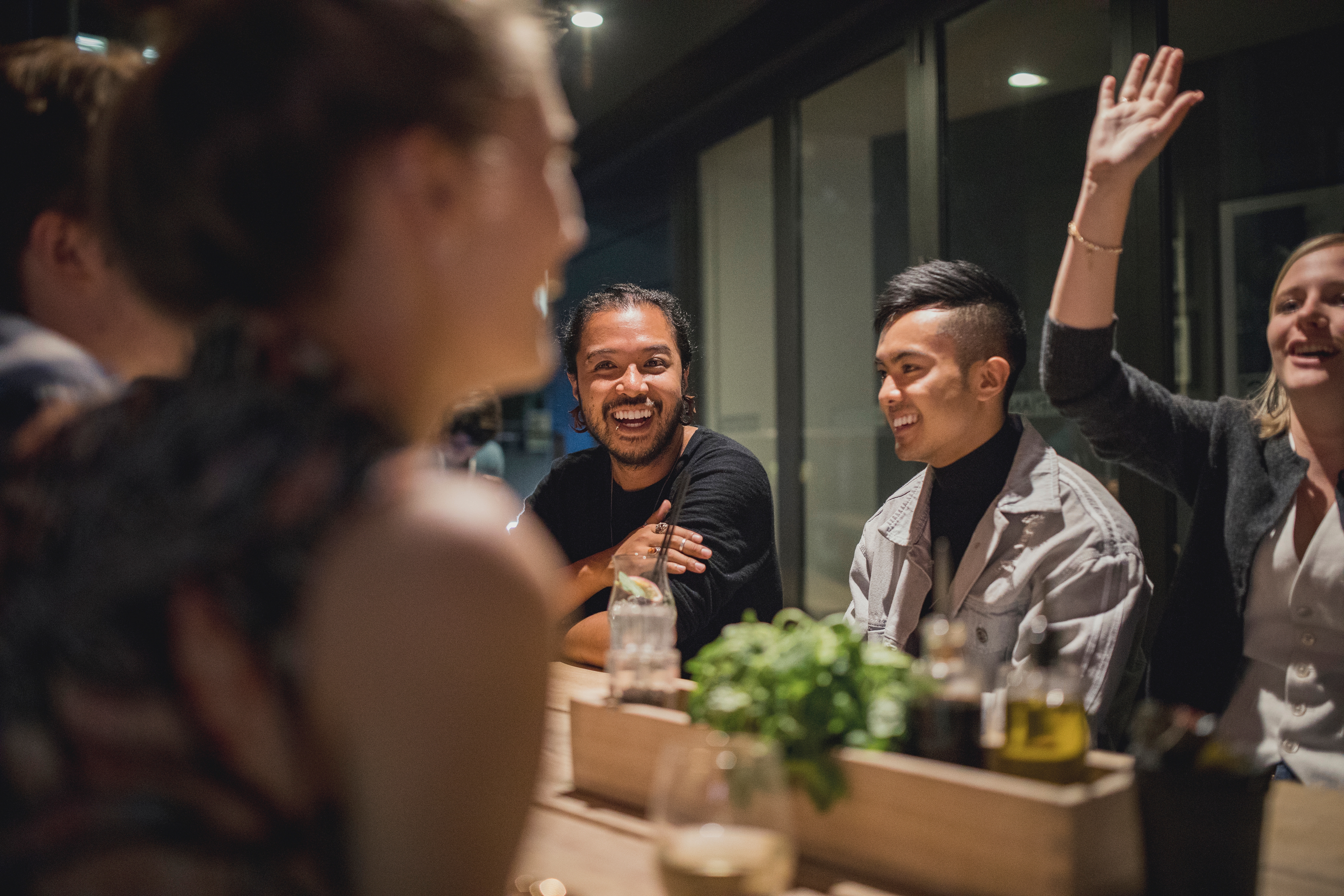Group of young adults enjoying a lively conversation at a restaurant, reflecting Berlitz’s focus on social confidence through language immersion.

