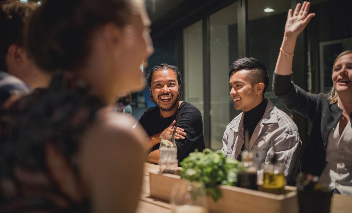 Group of young adults enjoying a lively conversation at a restaurant, reflecting Berlitz’s focus on social confidence through language immersion.