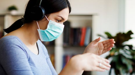 Woman wearing a mask and headset participating in a virtual session to learn Haitian Creole online
