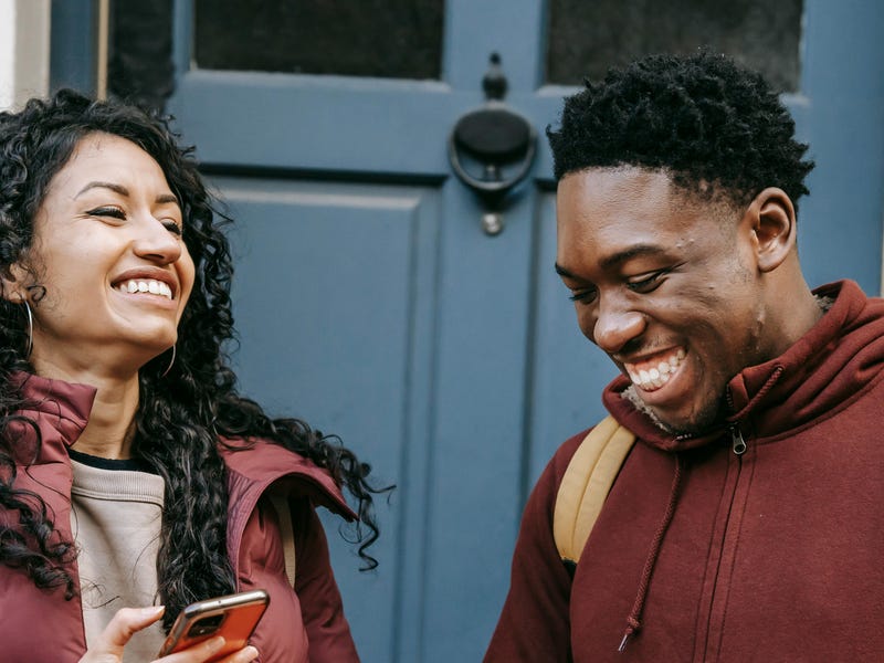 A woman holding he phone and talking to her friend about the future perfect tense in English while smiling