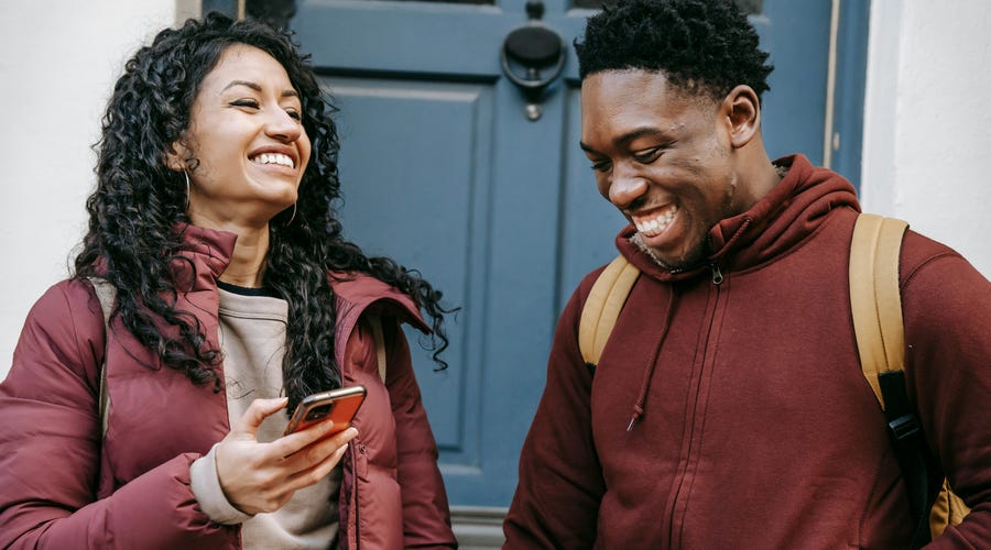 A woman holding he phone and talking to her friend about the future perfect tense in English while smiling