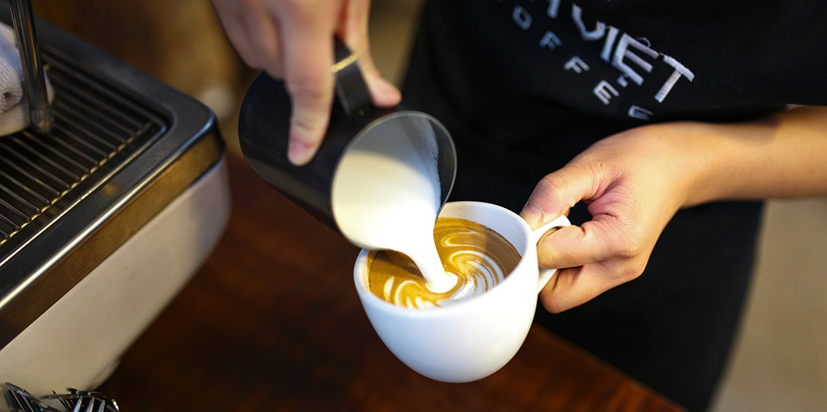 Barista pouring a cup of coffee in Italian cafe.