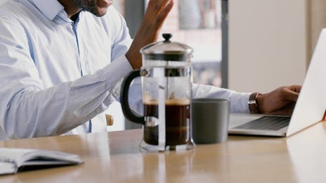 Smiling man waving during an online Finnish language class from home