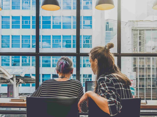Two students working together on a laptop in a modern high-rise space, symbolizing flexible learning options through online German classes.