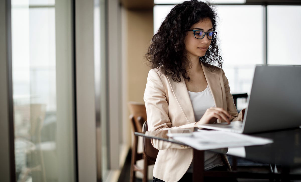 Professional woman learning Kannada online at a modern workspace using her laptop