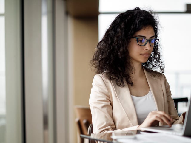 Professional woman learning Kannada online at a modern workspace using her laptop