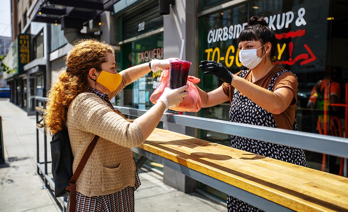 Woman saying goodbye and thank you in Spanish while collecting her food and drink order.