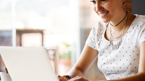 Smiling young professional working remotely on a laptop, representing the flexible and global opportunities available through Berlitz careers.