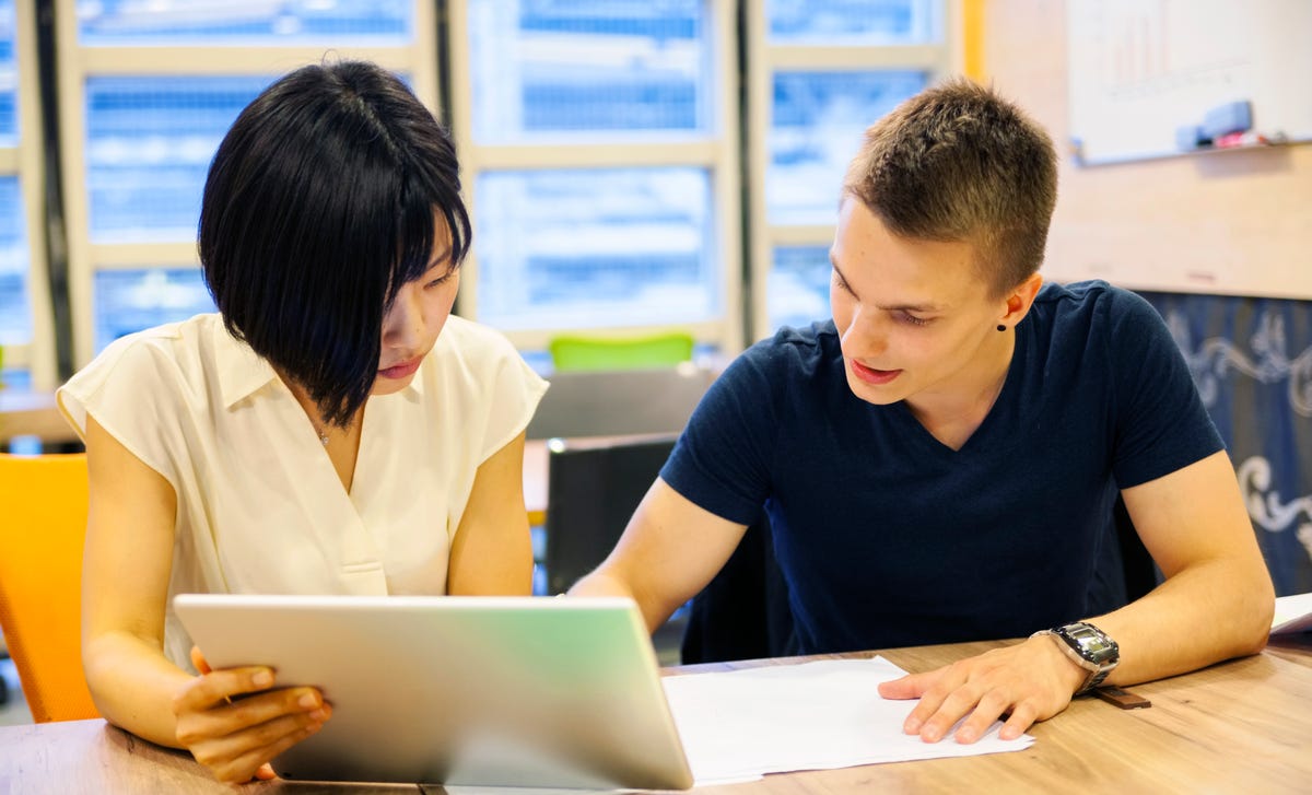 Two young adults studying together in a modern learning center, representing Berlitz locations where language classes and student collaboration thrive.