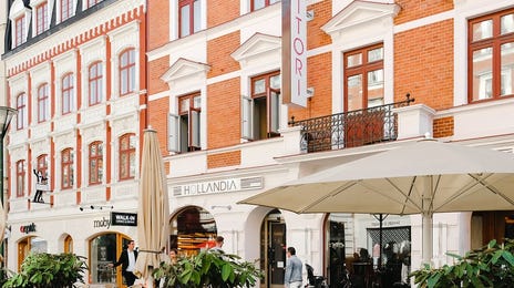 An outdoor café with chairs, potted plants, and a historic street scene in Sweden, perfect for offering Swedish language classes in a relaxed and cultural environment.