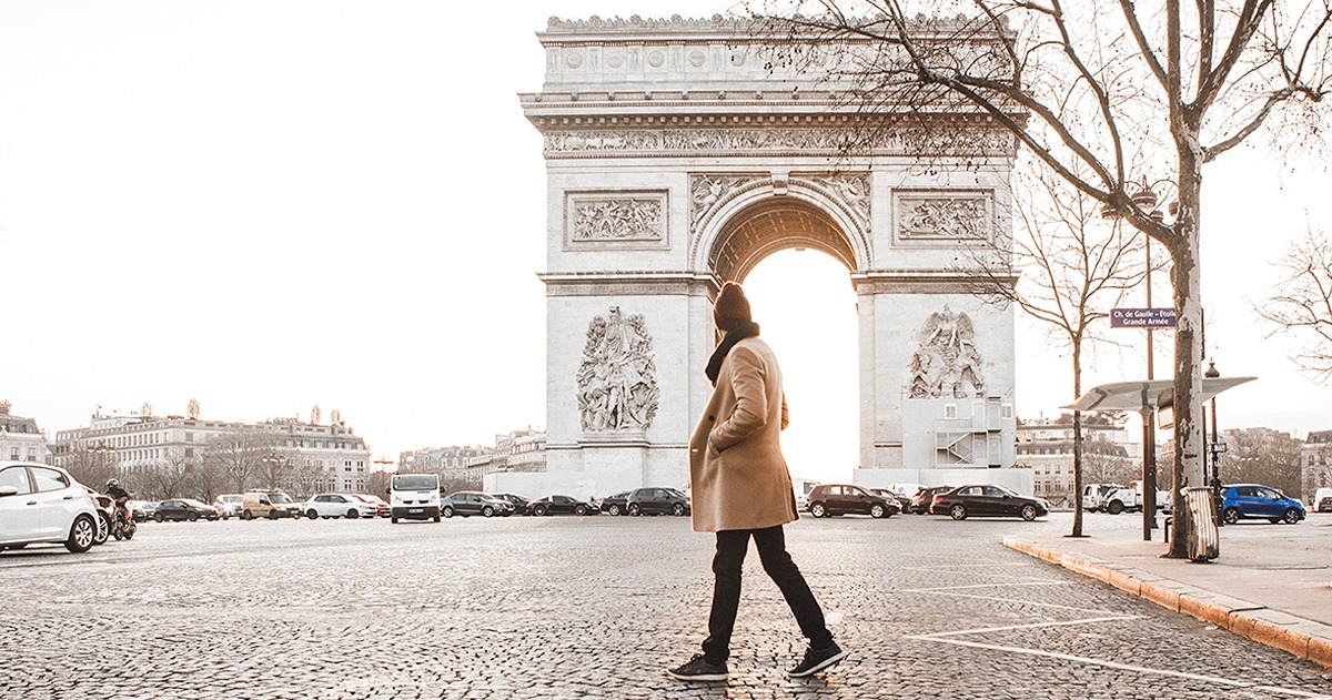 Man walking in front of the Arc de triomphe.