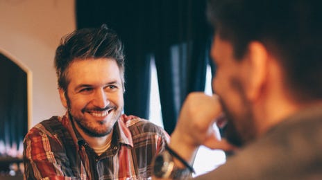 Two men practicing conversation to learn Bulgarian at a cozy cafe setting.