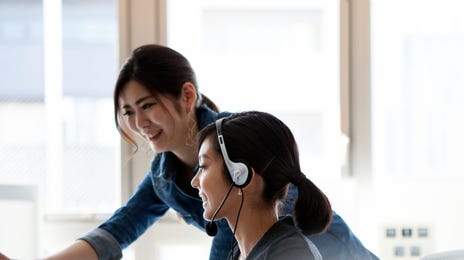 Instructor guiding a student through Berlitz language testing on a desktop computer