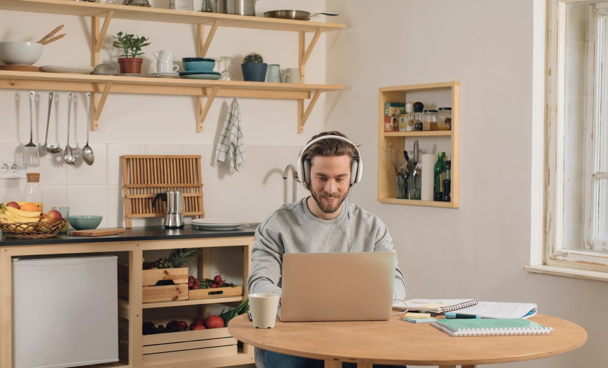 Man wearing headphones learning Finnish online at home in a cozy kitchen setup