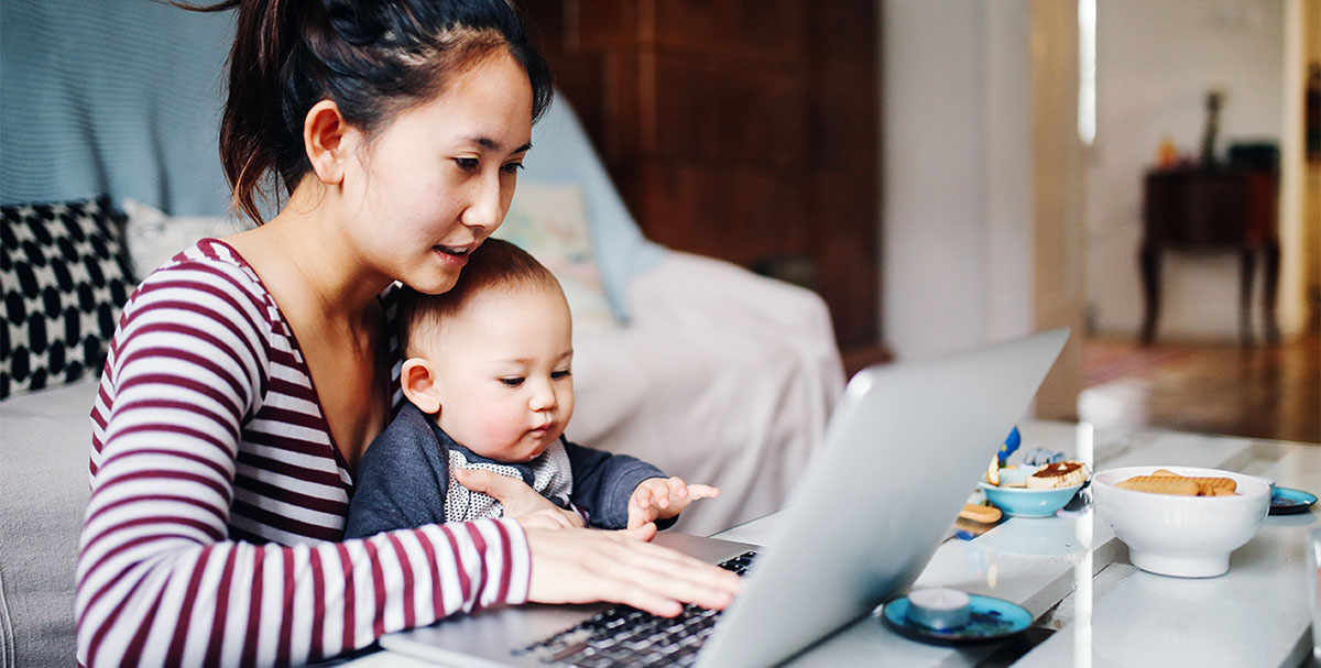 Mother formatting a formal or business email in German whilst looking after her baby.