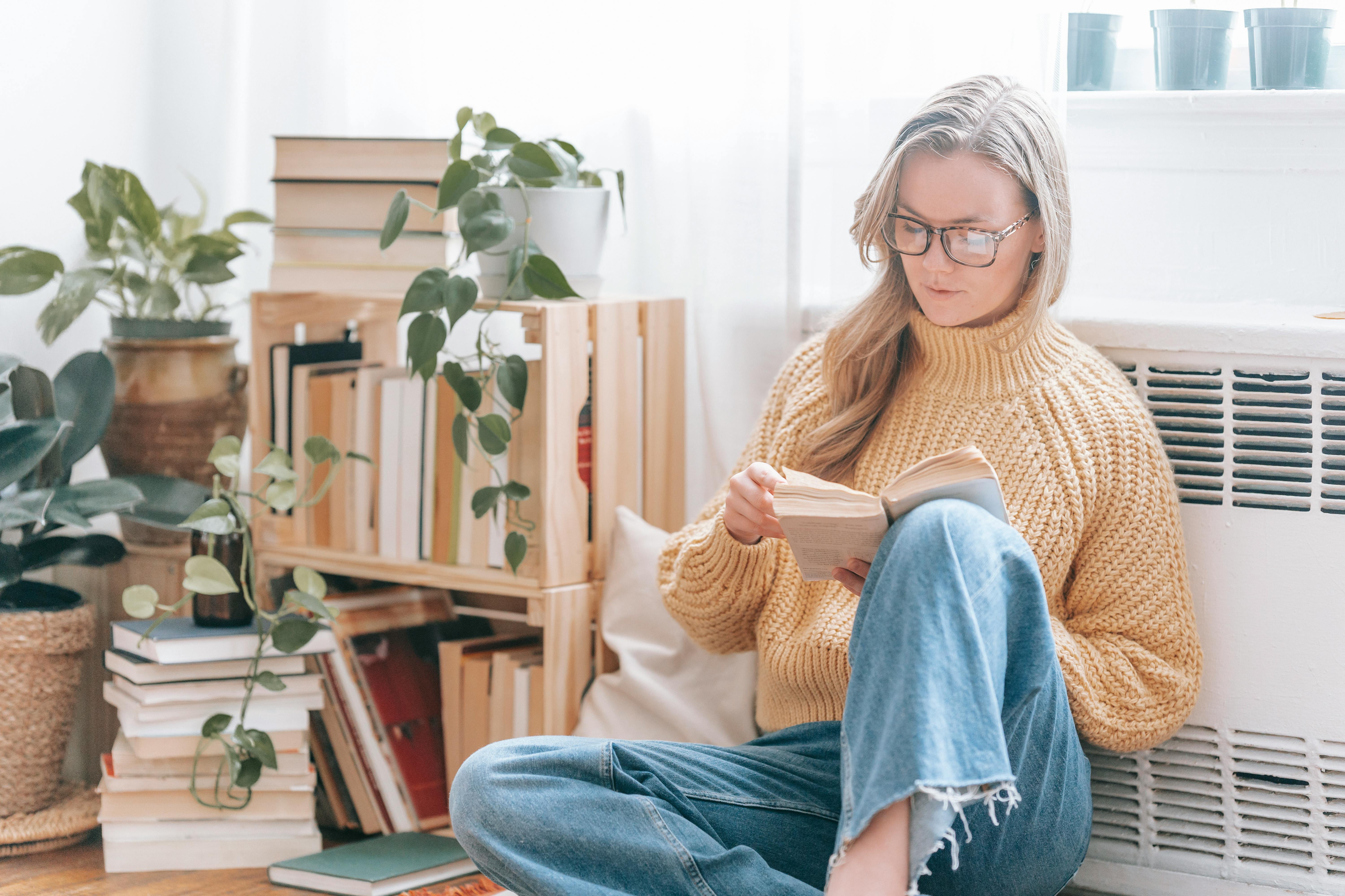 Woman in glasses holding a book and reading about the present perfect tense