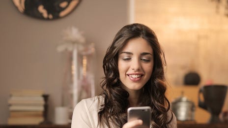 Happy woman learning Hebrew online via phone and computer in her home