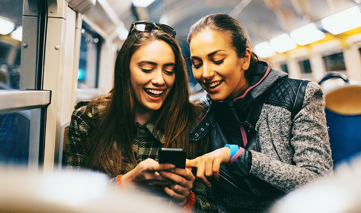 Two women learn how to tell the time in Spanish on the train.