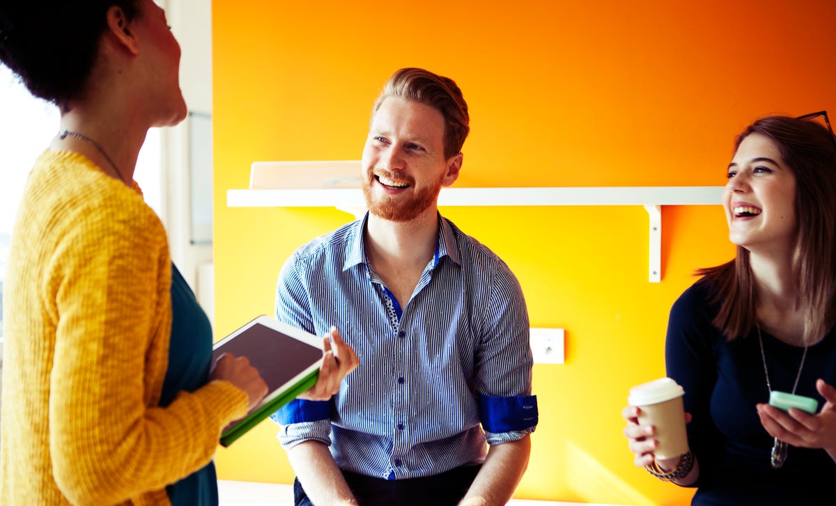 A group of young adults engaged in a lively discussion in a bright classroom, representing the interactive and supportive experience of learning Haitian Creole together.