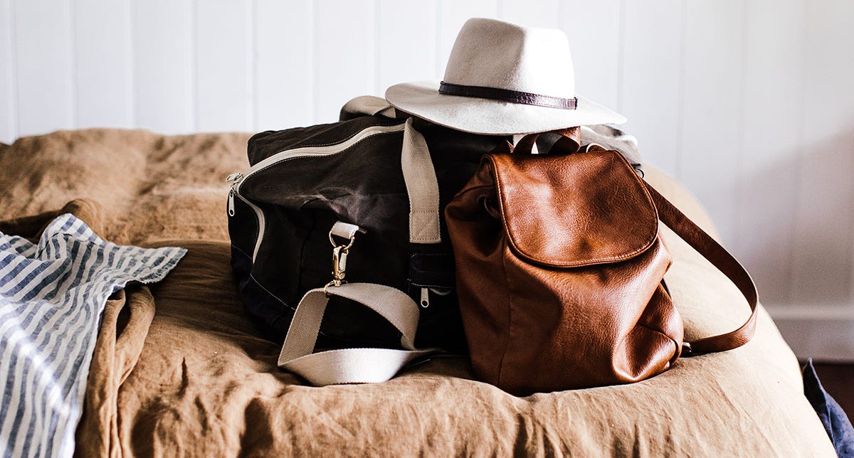 Travel accessories such as hat, leather bag, and tote bag in Italian.