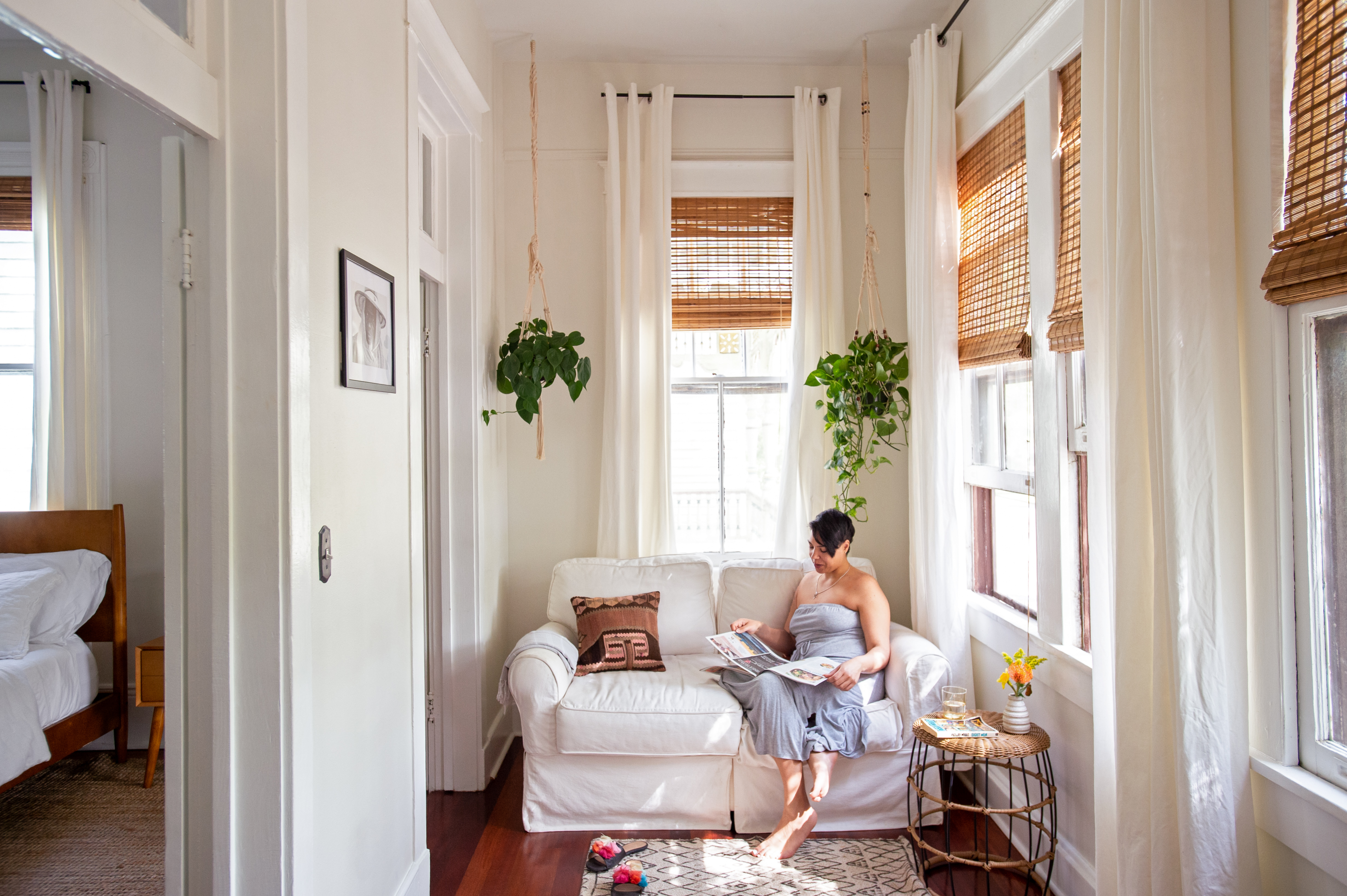 Žena sedi na belom kauču i čita časopis.