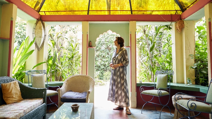 Mara b'libsa b'disinn fil-griż u fl-abjad bilwieqfa fuq terrazzin b'saqaf isfar imdawwra bix-xtieli.