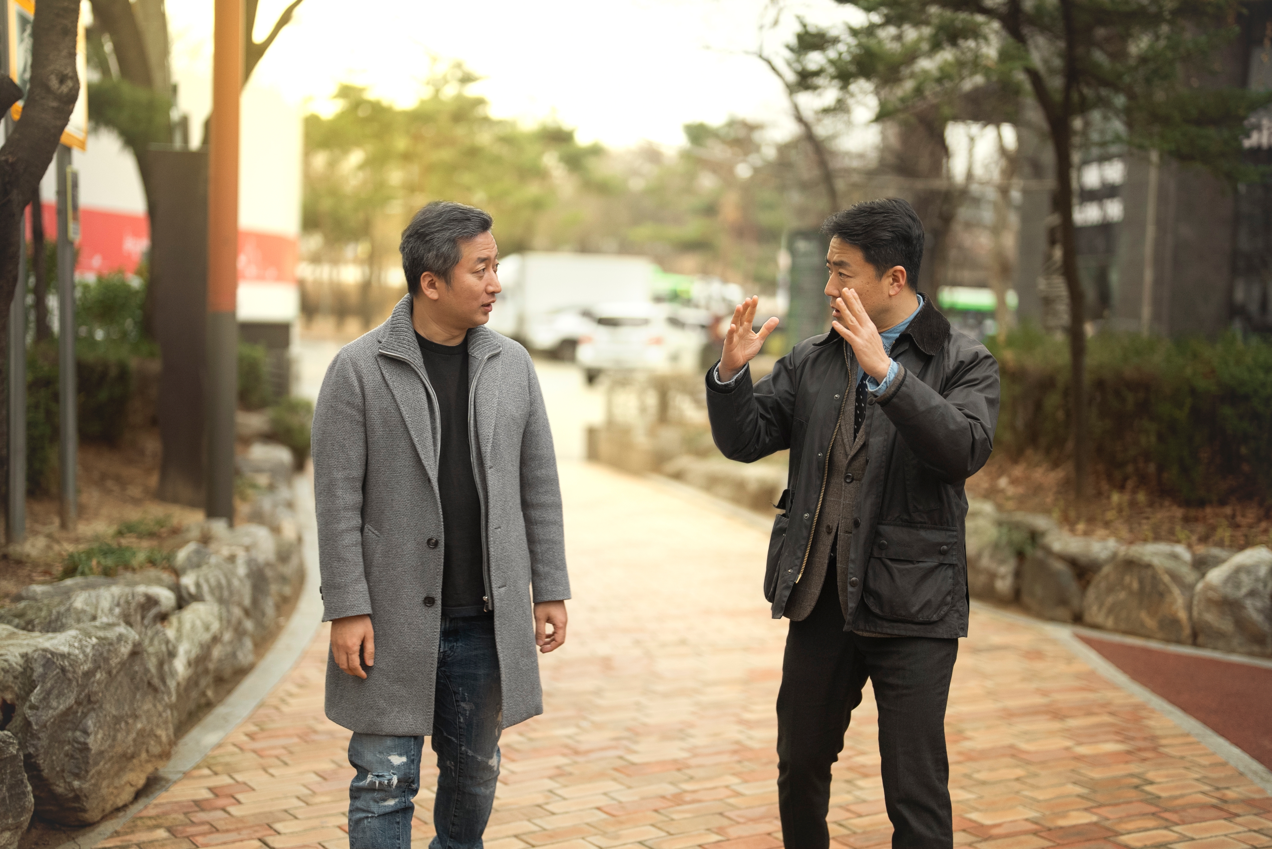Una persona con un abrigo gris conversa con otra persona con una chaqueta negra en una pasarela.