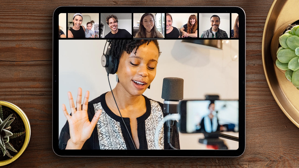 A tela de um iPad mostra um anfitrião de experiências online em frente a um microfone, cantando para os hóspedes