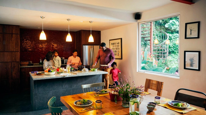 Two adults and their child cook a meal in a cozy kitchen.
