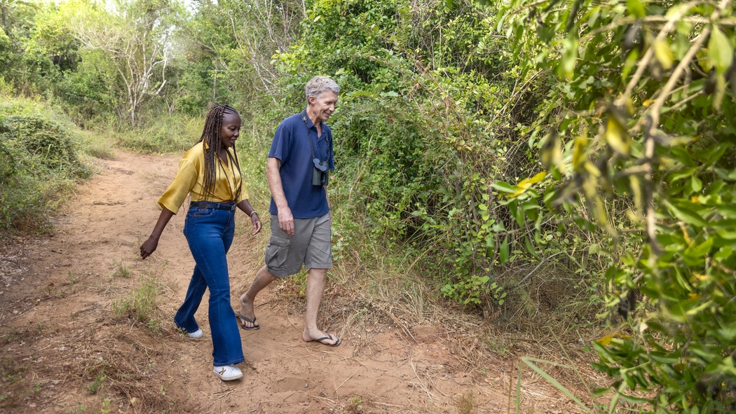 Deux personnes marchent sur un chemin de terre dans une zone naturelle.