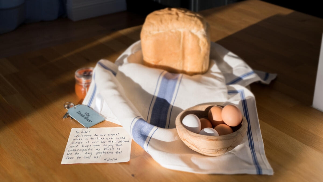 Una pagnotta, delle uova e delle chiavi sono posati su un tavolo accanto a un biglietto scritto a mano.