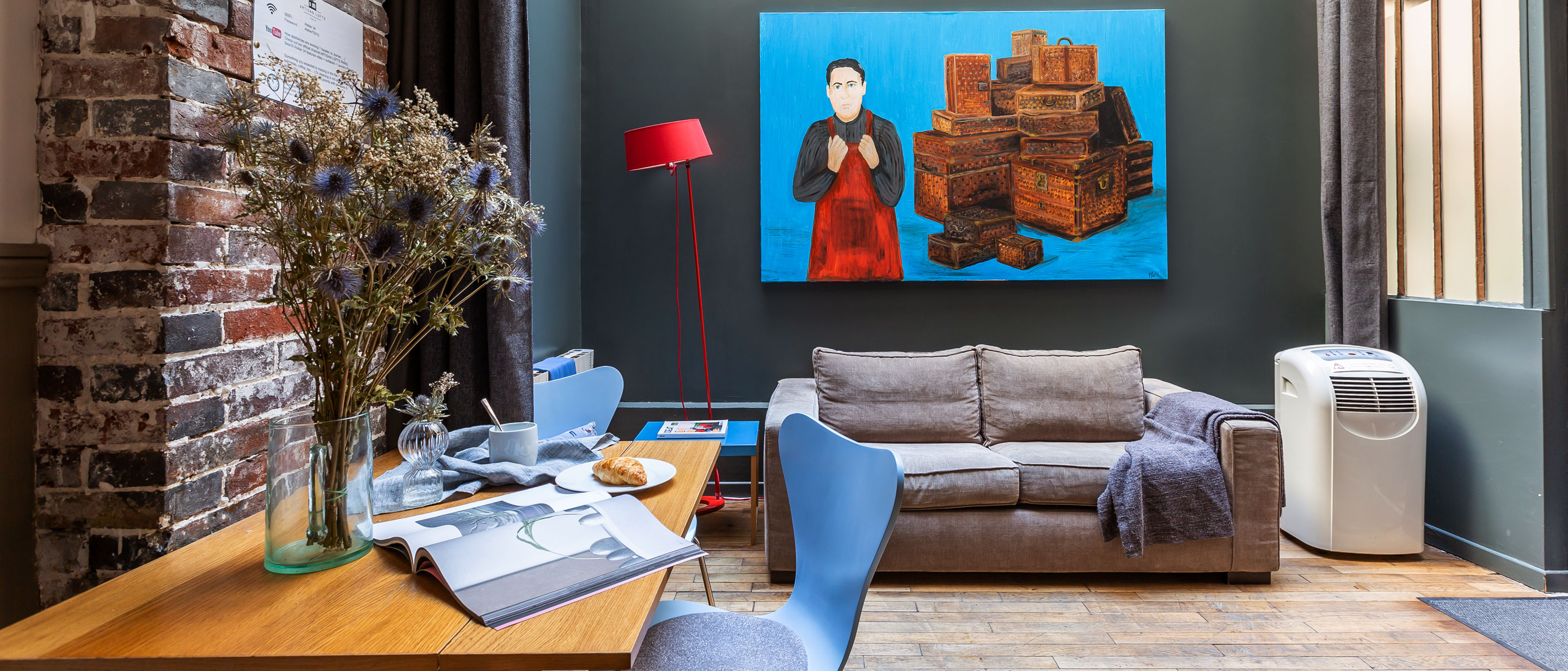 Um espaço chique com uma secretária, um sofá confortável e uma grande obra de arte.