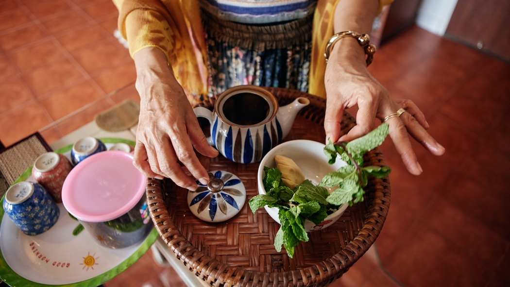 A woman prepares tea on a serving platter.