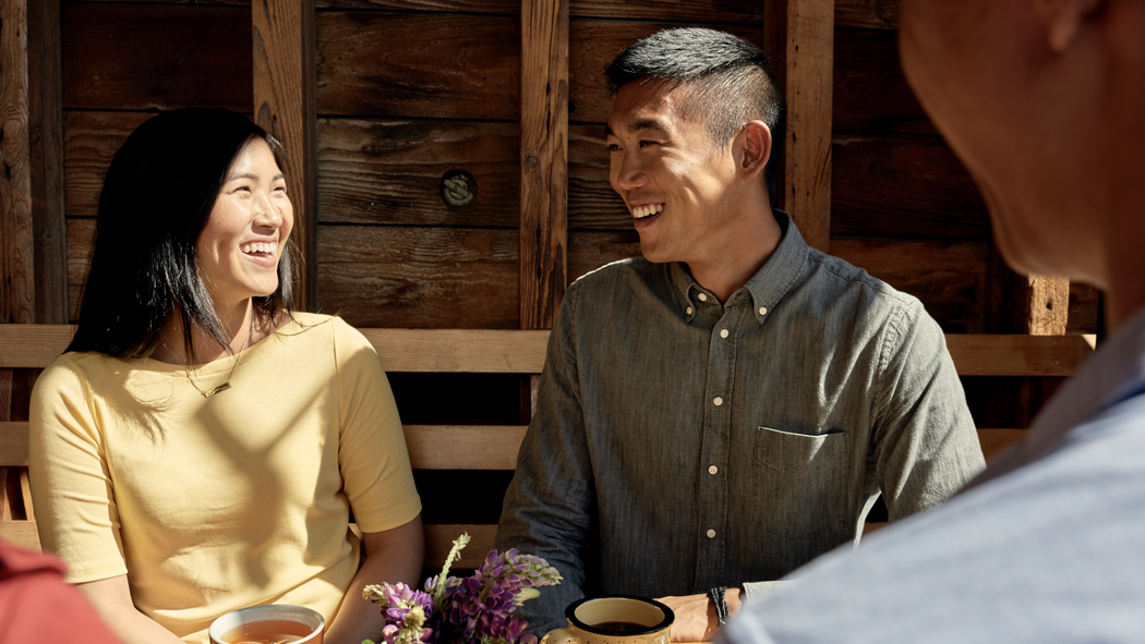 Un uomo e una donna si guardano sorridendo mentre bevono un tè.