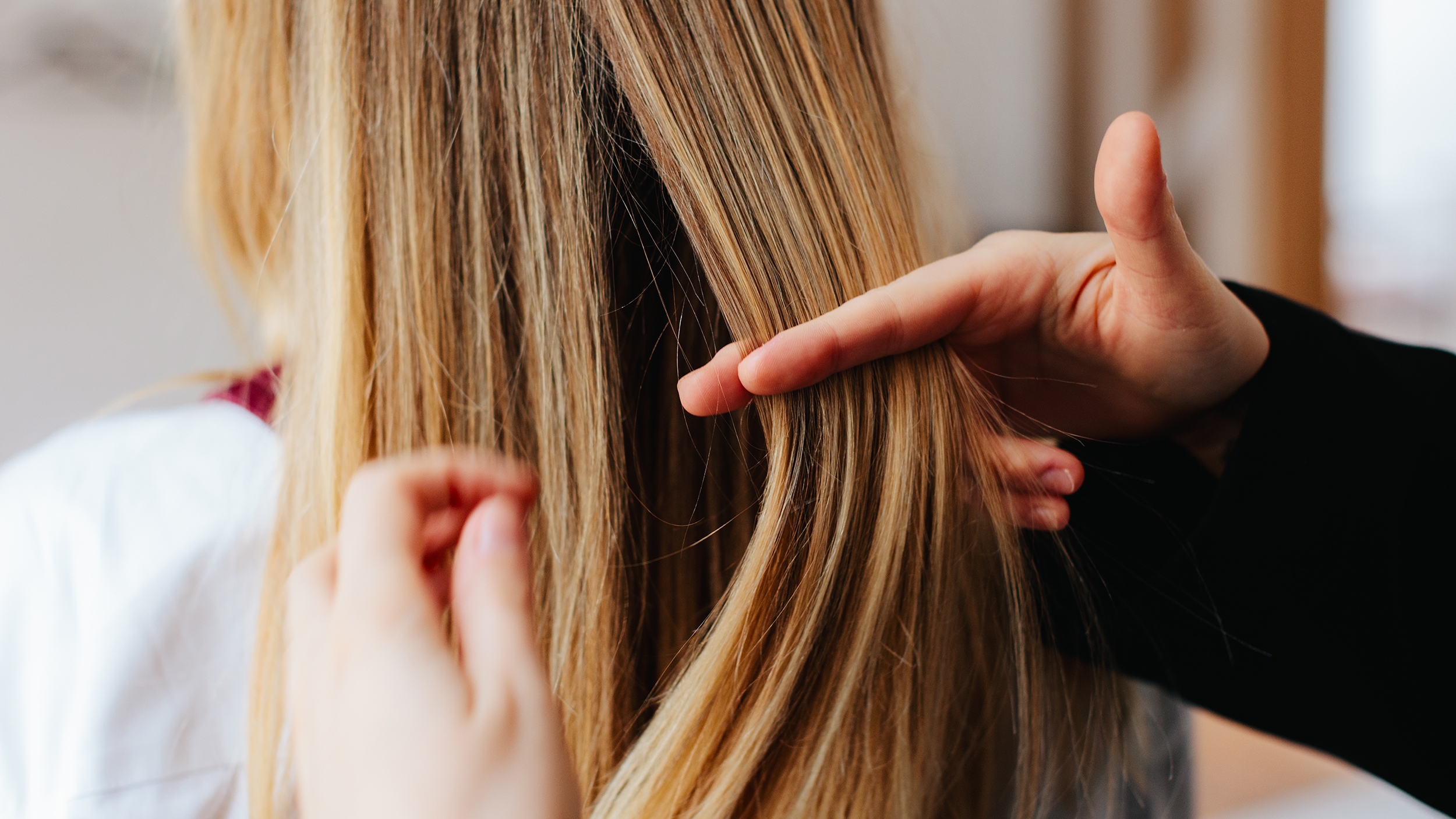 एक व्यक्ति किसी अन्य व्यक्ति के लंबे भूरे बालों में हाथ फिरा रहा है।