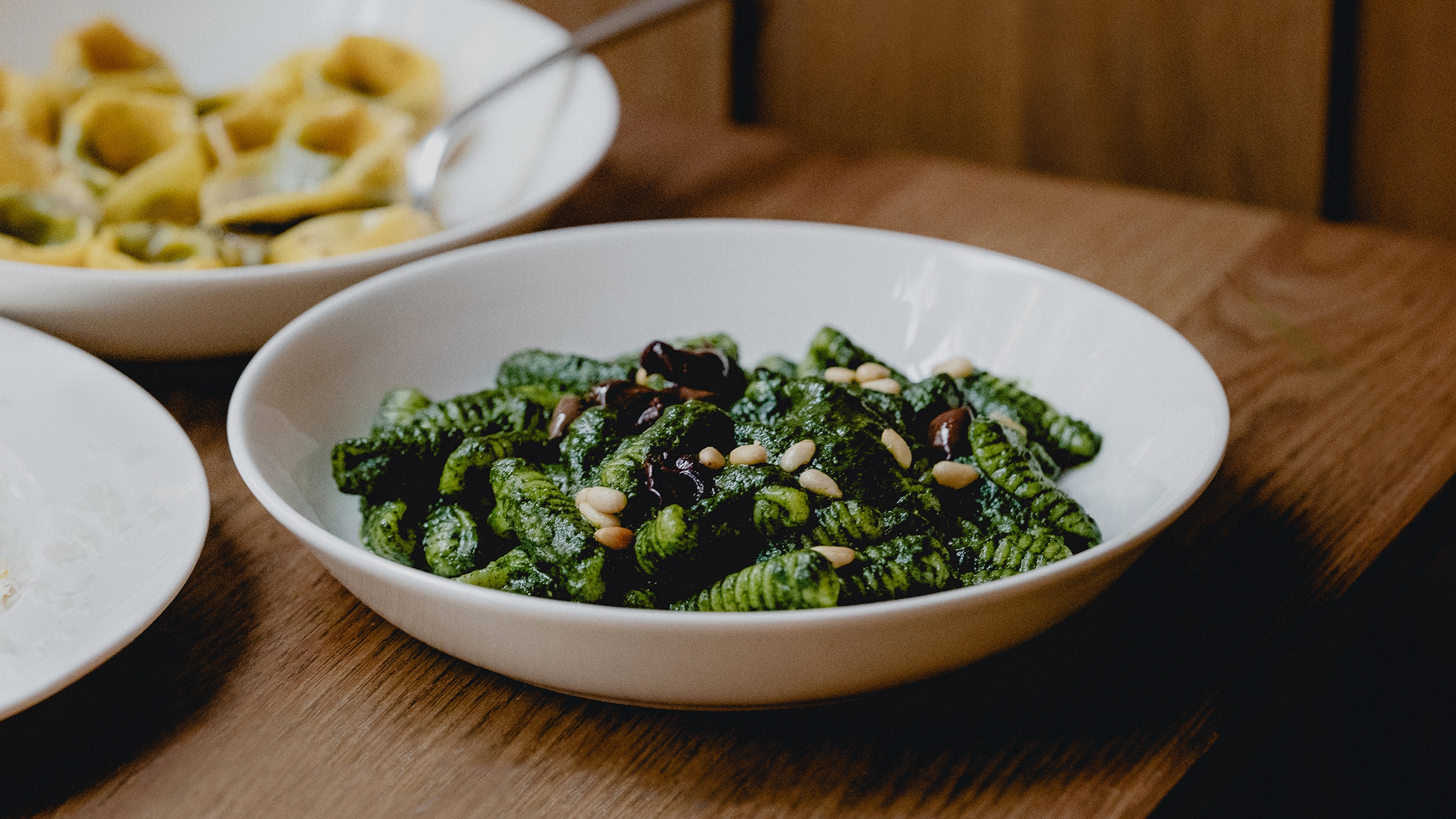 Dos tazones blancos con pasta sobre una superficie de madera.