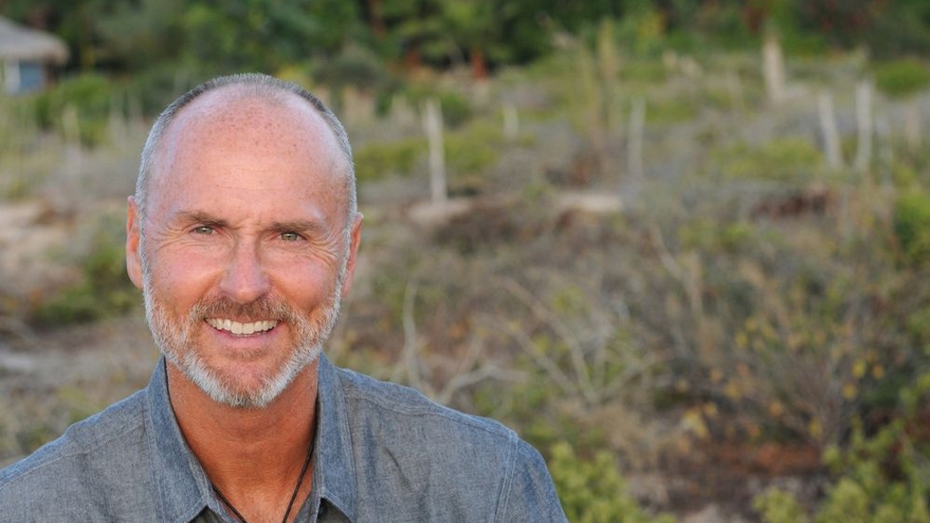 Host and entrepreneur Chip Conley smiles at the camera with his backyard in the background.
