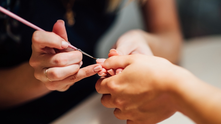 Uma manicure usa um pincel durante o serviço.