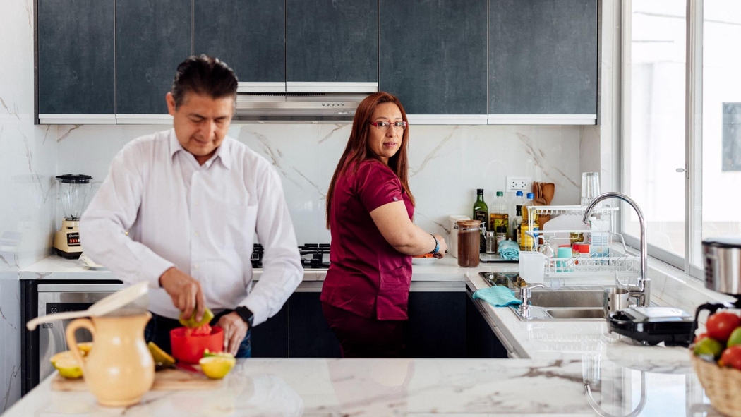 Two Airbnb.org Hosts work at a kitchen worktop. One person squeezes lemons while the other washes dishes.