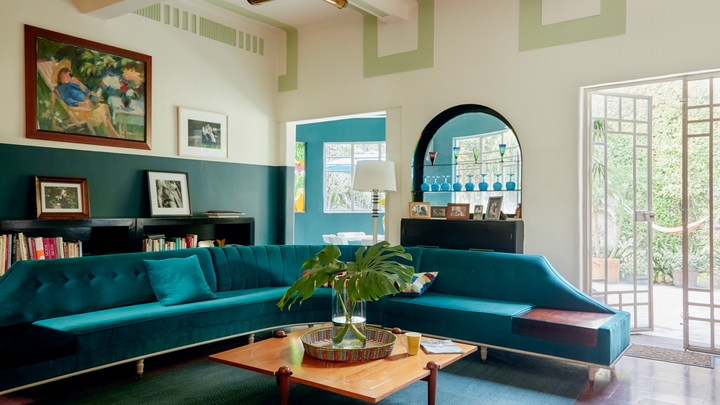 Una sala de estar amplia y luminosa con un sofá turquesa.