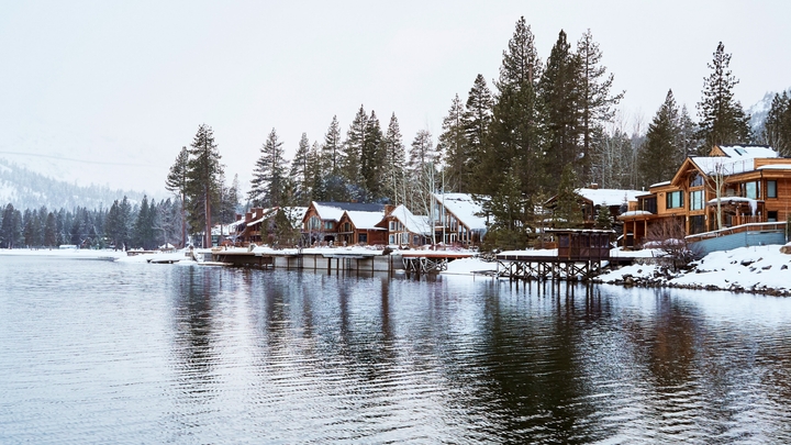 Several houses sit alongside a body of water in the wintertime.