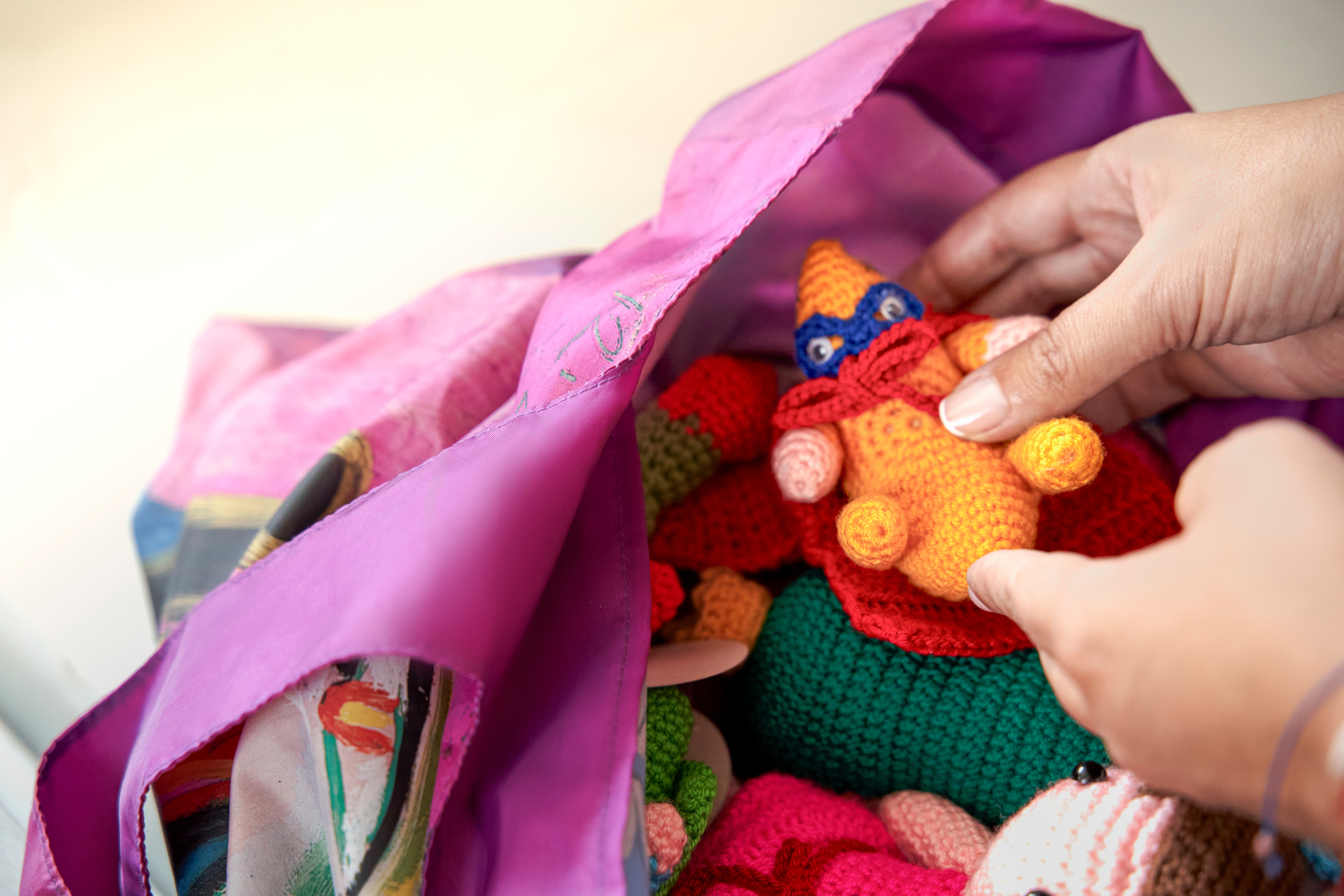 Մի մարդ ձեռագործ տիկնիկ է պահում մի քանի տիկնիկներով տոպրակի մեջ։