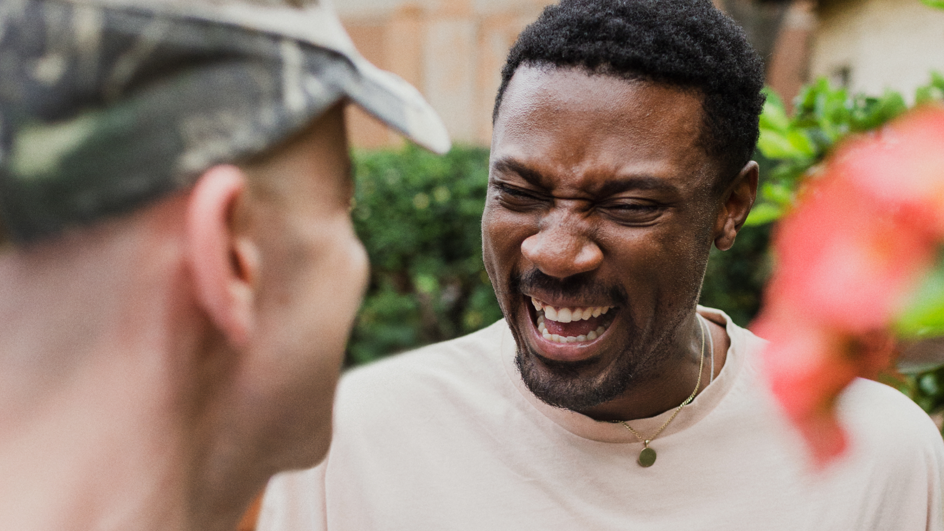 To personer griner sammen, den ene vender mod kameraet og den anden vender væk.