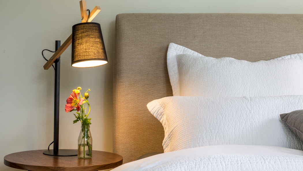 ベッド脇のナイトスタンドにランプと花瓶が置いてある。