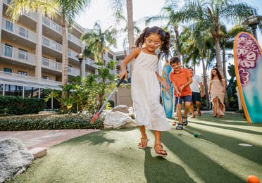 Family playing mini golf outdoors at Cape Canaveral Beach Resort in Florida.