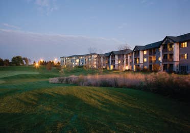 Outdoor golf course at sunset with view of property buildings in the background at Lake Geneva Resort in Wisconsin.