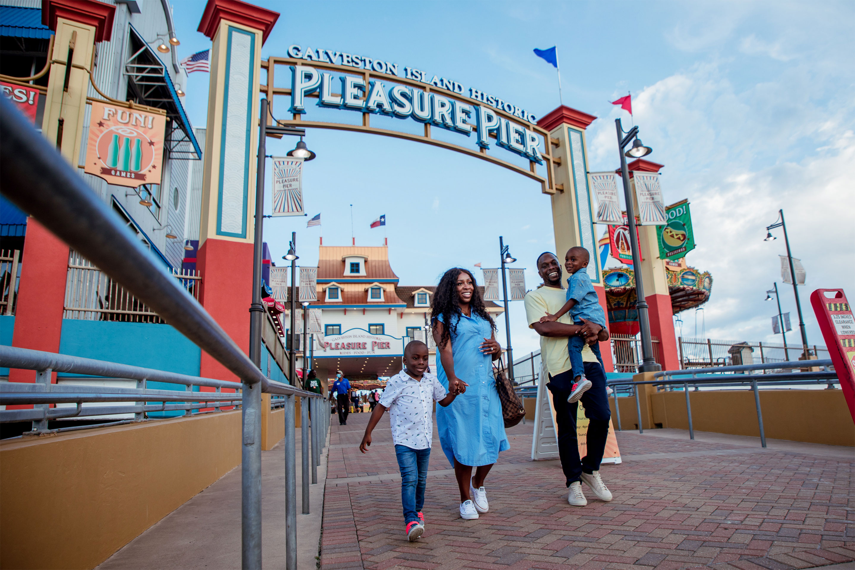 A woman, man and two young boys walk down a pier.
